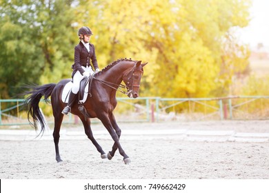Jonge ruitervrouw op baaipaard die geavanceerde test op dressuurcompetitie uitvoert. Paardensport evenement achtergrond met kopie ruimte