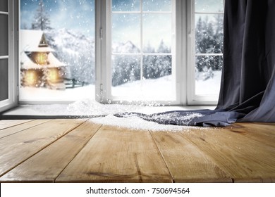 製品またはプロモーション テキスト用の空き領域を持つ木製のテーブル。降雪でウィンドウを開きます。村の端にある冬の森の山々と小さなドックの風景。