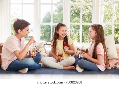 Niños sentados en el asiento de la ventana comiendo helados