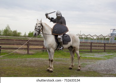 騎士が剣を手に白馬に乗っています。鎧の男。チェーンメールのモデル。中世の鎧