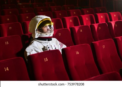 Bir sinema astronotu patlamış mısır yerken ve filmin tadını çıkarırken bir film izliyor. Kavram: sinema ve uzay filmleri, diğer dünyanın filmi, gerçeküstü durumlar.