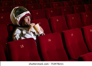 Bir sinema astronotu patlamış mısır yerken ve filmin tadını çıkarırken bir film izliyor. Kavram: sinema ve uzay filmleri, diğer dünyanın filmi, gerçeküstü durumlar.