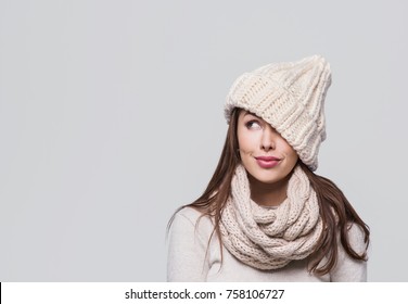Schöne Frau, die aufschaut. Auf grauem Hintergrund isoliert. Lächelndes Mädchen, das warme Kleidung, Winterporträt trägt