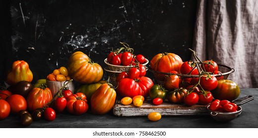 Heirloom variety tomatoes on dark rustic table text abundance ripe tomatoes