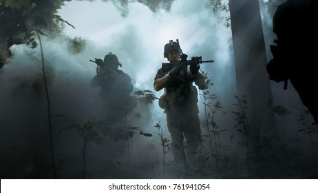 Voll ausgerüstete Soldaten in Tarnuniform, die den Feind angreifen, Gewehre, die schussbereit sind. Militäroperation in Aktion, Trupp läuft in Formation durch kalten, dichten Rauchwald.