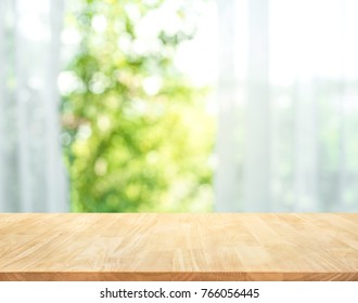 Leeg van houten tafelblad op vervaging van gordijn met raam uitzicht groen van boomtuin achtergrond. Voor montage productweergave of ontwerp belangrijke visuele lay-out