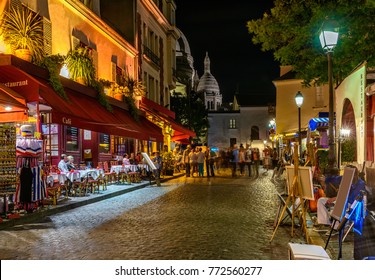Vista nocturna típica de acogedora calle con mesas de café y caballetes de pintores callejeros en el barrio de Montmartre en París, Francia. Arquitectura y monumentos de París. Postal de Paris