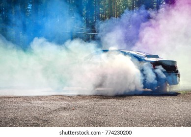 Mobil drift memanaskan ban sebelum start, menunggu balapan dimulai. Asap biru dan ungu di sekitar.