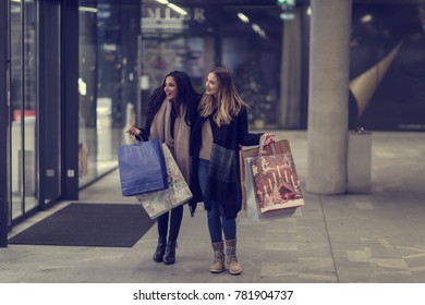 zwee erwuesse Fraen op hir Mëtternuecht Shopping Spree an engem schéin Stad Zentrum, schwéier gelueden mat Chrëschtdag Cadeauen, Shopping, iwwerdeems Spadséiergank laanscht Buttek Fënsteren.