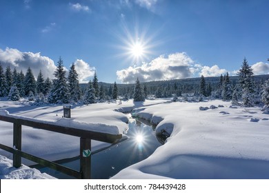 小川と木の橋のある冬の山の風景。木々と太陽が水に映ります。イゼラ山脈、チェコ共和国、ヨーロッパ。