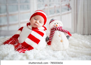 Chân dung Giáng sinh của cậu bé sơ sinh nhỏ bé dễ thương, đội mũ ông già Noel và đồ chơi người tuyết nhỏ dễ thương, chụp studio, thời gian mùa đông
