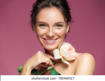 Beautiful girl with rose. Photo of happy brunette girl on pink background. Youth and skin care concept