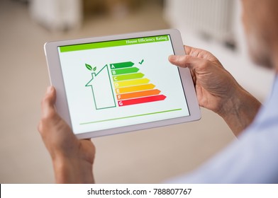 Hand holding digital tablet and looking at house efficiency rating. Detail of house efficiency rating on digital tablet screen. Concept of ecological and bio energetic house. Energy class.