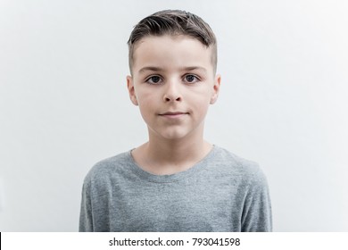 Foto des entzückenden jungen glücklichen Jungen, der Kamera betrachtet. Auf dem weißen Hintergrund isoliert
