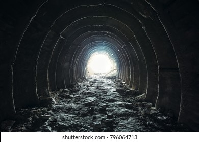 Light and exit in the end of dark long tunnel or corridor, way to freedom concept. Industrial round chalk mine passage with hole, perspective, toned