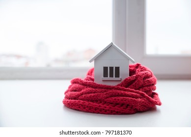 casa en invierno - concepto de sistema de calefacción y clima frío y nevado con modelo de una casa con gorra de punto