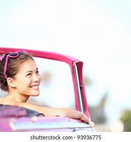 Autofrau, die glücklich lächelt und Autoreise-Reiseurlaub genießt. Junge Retro-Frau in rosa Cabrio-Oldtimer, die zur Seite schaut. Schöne junge gemischtrassige kaukasische / chinesische Asiatin in Havanna, Kuba