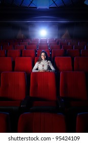 schöne junge Frau sitzt allein in einem leeren Kino
