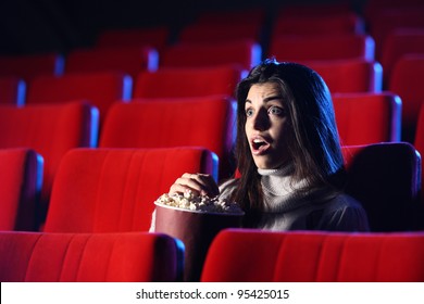 film d'horreur : portrait d'une jolie fille dans une salle de cinéma vide, son visage exprime la surprise et la peur