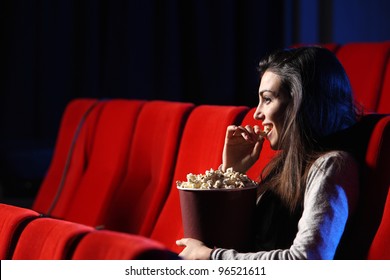 Portrait d'une jolie jeune femme, elle mange du pop-corn et sourit.