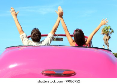 Vrijheid - gelukkig gratis paar in auto rijden in roze vintage retro auto juichen vrolijk met opgeheven armen. Vrienden gaan op road trip reizen op zomerdag onder zon blauwe hemel.