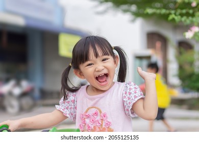 Portrait​ image of​ 3-4 years old​ childhood​ child. Face of smile and 
laugh Asian​ girl in head shot. Happy​ kid playing​ at the park playground. In summer or spring​ season.