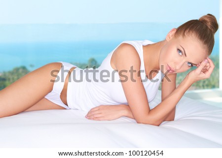 Cute woman lying on white bed at modern luxury room