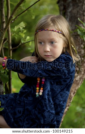 Portrait of a little girl sitting on a branch of an apple tree on a beautiful summer afternoon