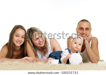 family of four people lying on the carpet on light background