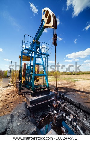 Landscape with oil pump under blue sky with clouds in a sunny day