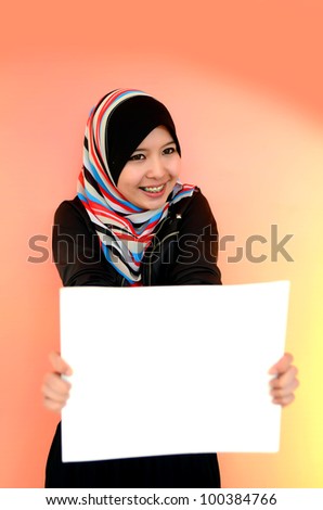 Portrait of a beautiful Muslim woman holding a white paper with smile, isolated on orange background
