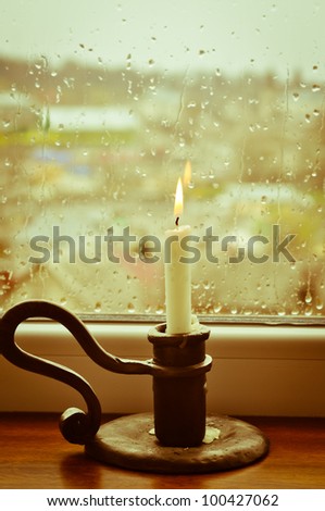A stylized picture of a lit candle on a rainy day
