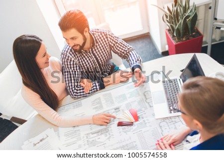 Young family couple purchase rent property real estate . Agent giving consultation to man and woman. Signing contract for buying house or flat or apartments. Choose the color of the walls