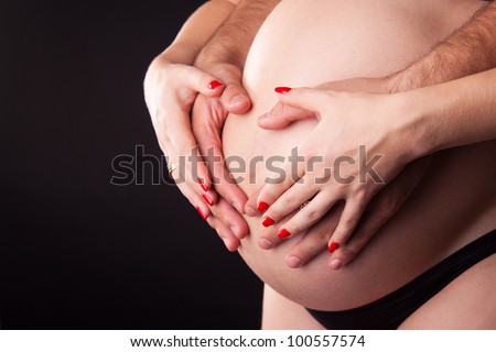 pregnant woman with her husbent holding tummy closeup