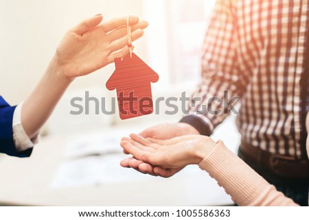 Young family couple purchase rent property real estate . Agent giving consultation to man and woman. Signing contract for buying house or flat or apartments. He holds a model of the house in hands