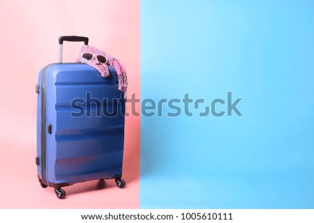 Blue plastic suitcase on soft pink and light blue pastel colored background, space for text
