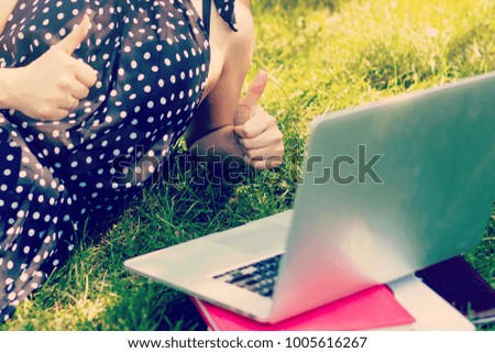 Young woman with laptop on green grass at park
