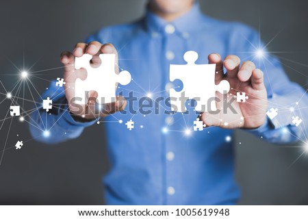 Businessman hands connecting puzzle pieces representing the merging of two companies or joint venture, partnership, Mergers and acquisition concept. Royalty-Free Stock Photo #1005619948