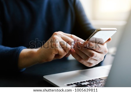 Man with a finger on the screen using a mobile phone in the office