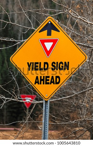 A warning Yield Sign Ahead sign in the fall