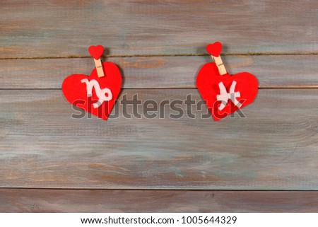 Capricorn and fish. signs of the zodiac and heart. wooden background. card. unusual handwork