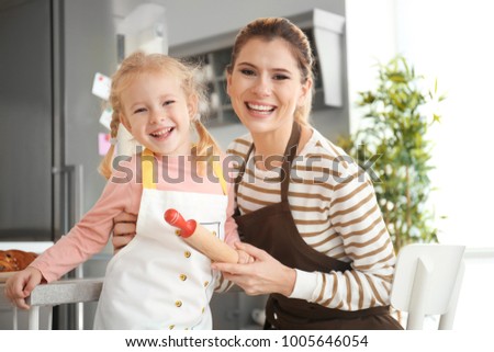 Mother and daughter in aprons indoors. Ready to make dough
