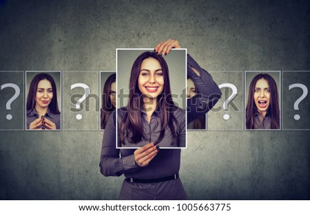 Young woman having split personality while posing with photos of different emotions. 