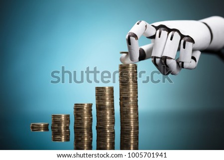 Close-up Of A Robot's Hand Stacking Golden Coins On Turquoise Background