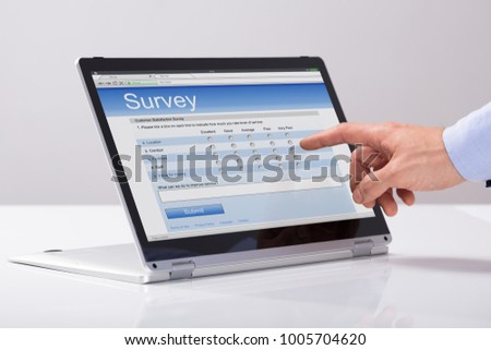 Close-up Of Businessman Filling Online Survey Form On Hybrid Laptop Over The White Desk