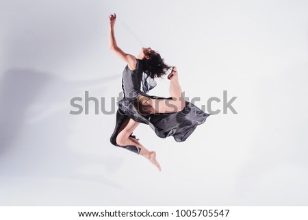 Modern contemporary dancer poses in front of the studio background. motion picture in the jump