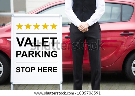 Close-up Of Male Valet Standing Near Valet Parking Sign