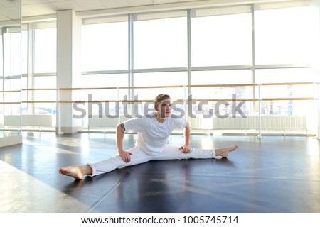 Young dancer doing close up backwards somersault . Male person training at gym studio. Concept of advertisement of dance school and successful graduates.