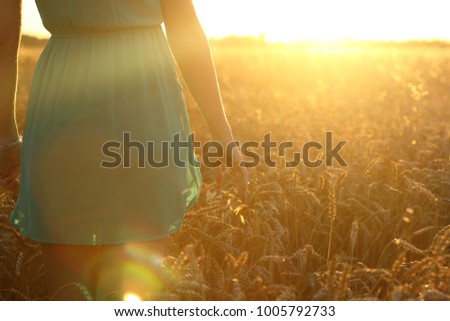 Beauty Girl Outdoors enjoying nature. Teenage Model girl in blue dress on the summer Field, Sunset Light.