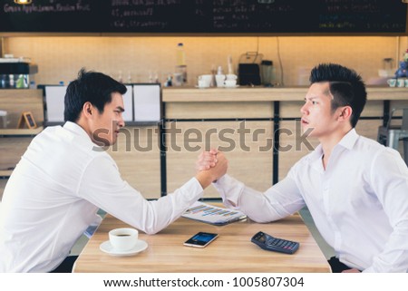 We are in a competitive business. We are in a competitive business. Two businessmen arm wrestling. Modern office background